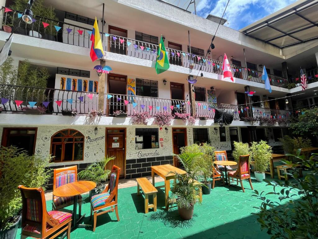 a courtyard of a hotel with tables and chairs and flags at El Jardín Escondido Party Hostel in Baños