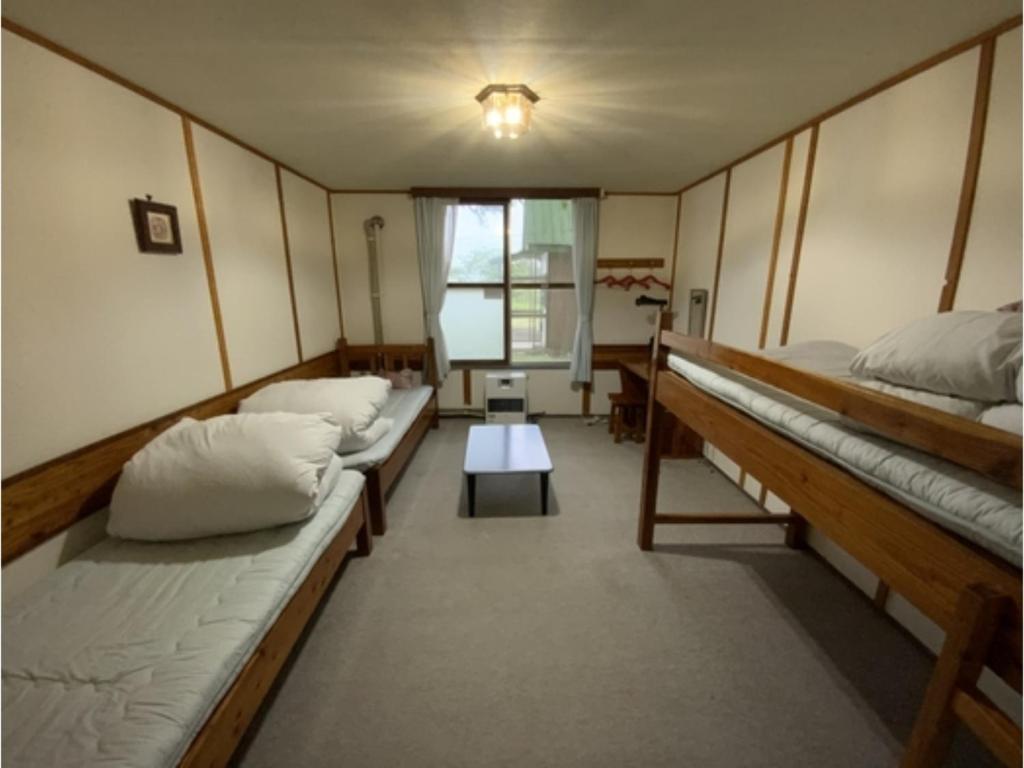 a room with three beds and a table in it at Mashuko Youth Hostel - Vacation STAY 00253v in Teshikaga