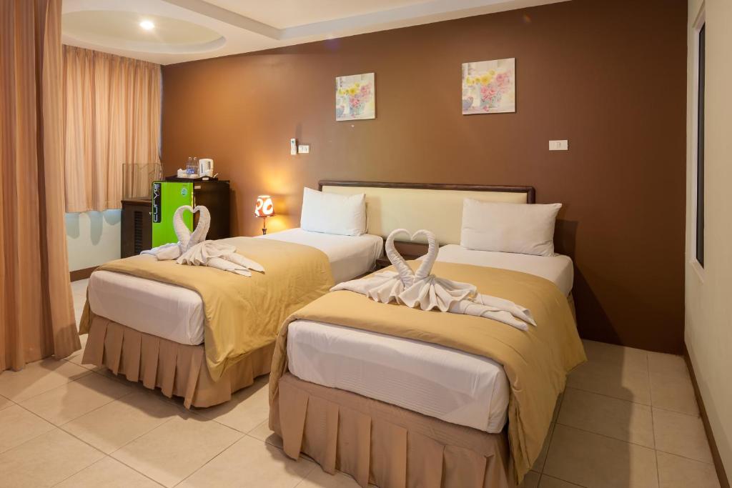 two beds in a hotel room with towels on them at The Right Resort in Pattaya Central