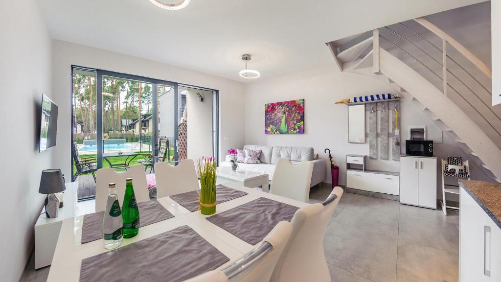 a dining room and living room with a table and chairs at Prestige House Apartament - 2 sypialnie z ogródkiem i basenem in Pobierowo