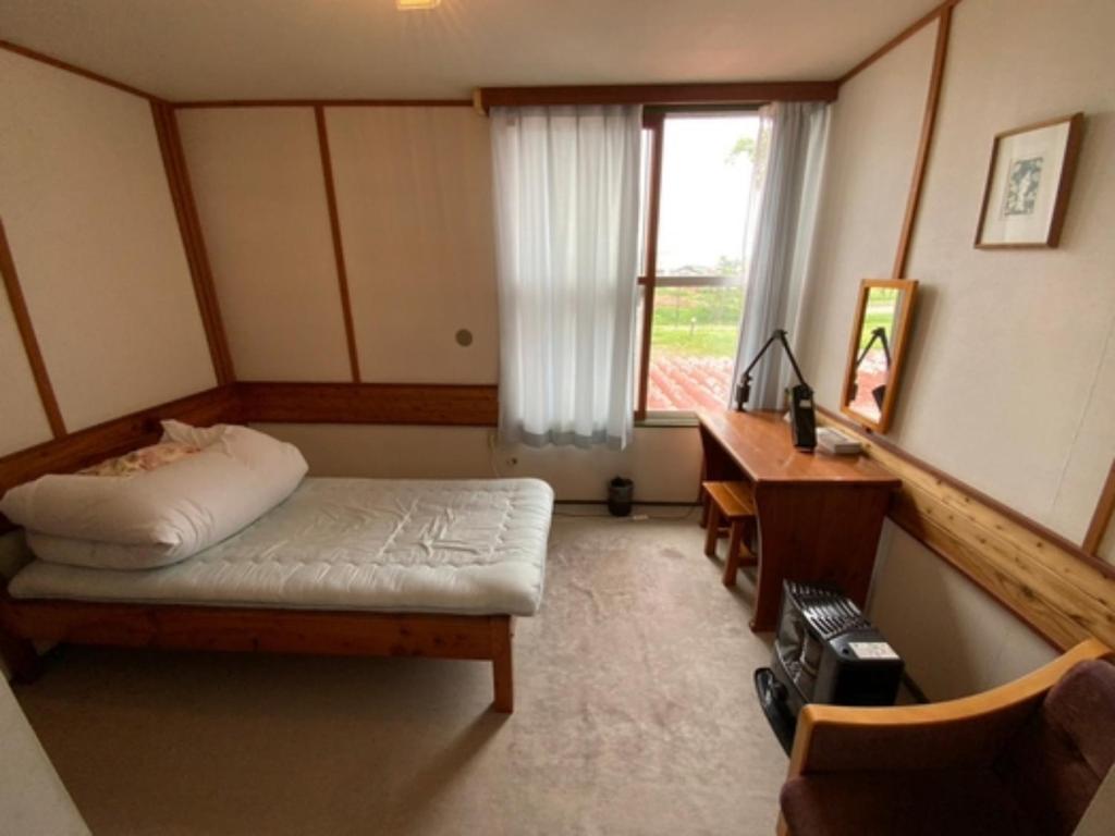 een slaapkamer met een bed, een bureau en een raam bij Mashuko Youth Hostel - Vacation STAY 00145v in Teshikaga