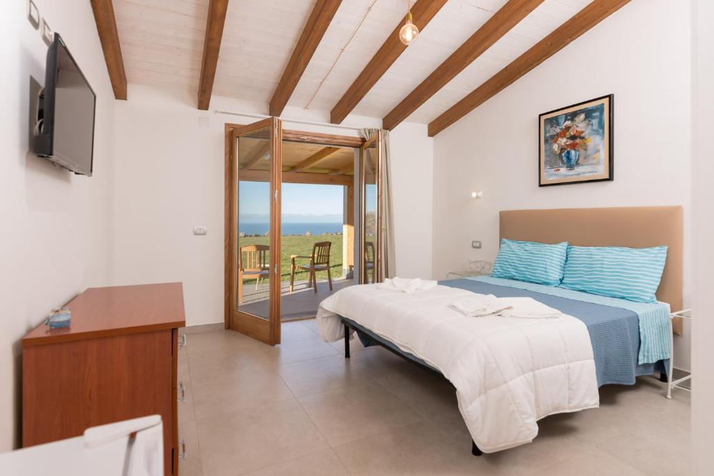 a bedroom with a bed and a television and a balcony at PARADAISE SUITES SEA VIEW SARDINIA, Bedda Ista in Castelsardo