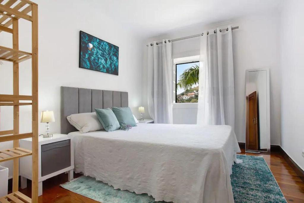 een witte slaapkamer met een bed en een raam bij Sea La Vie Madeira in Ribeira Brava