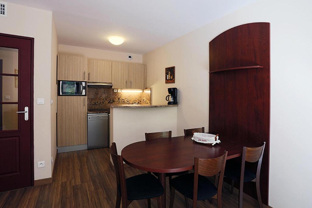 eine Küche und ein Esszimmer mit einem Tisch und Stühlen in der Unterkunft Résidence Serias - 2 Pièces pour 4 Personnes 594 in Germ