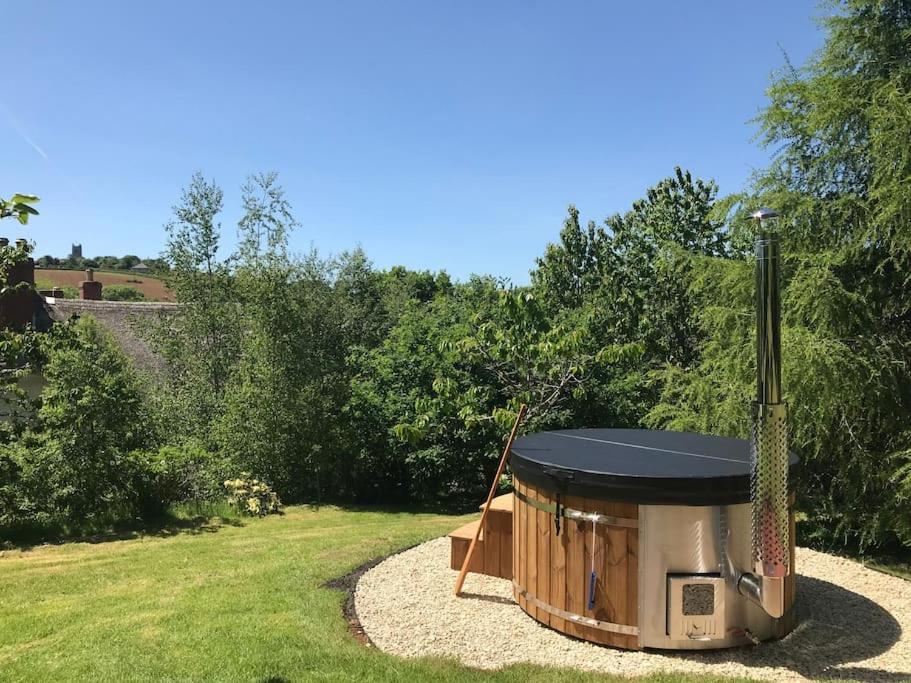 a barbecue grill in a garden with grass at Spacious country retreat in the heart of Devon. in Crediton