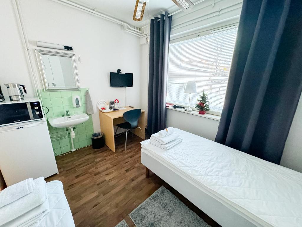 Habitación pequeña con cama y lavamanos en Hostelli Matkustajakoti, en Kuopio