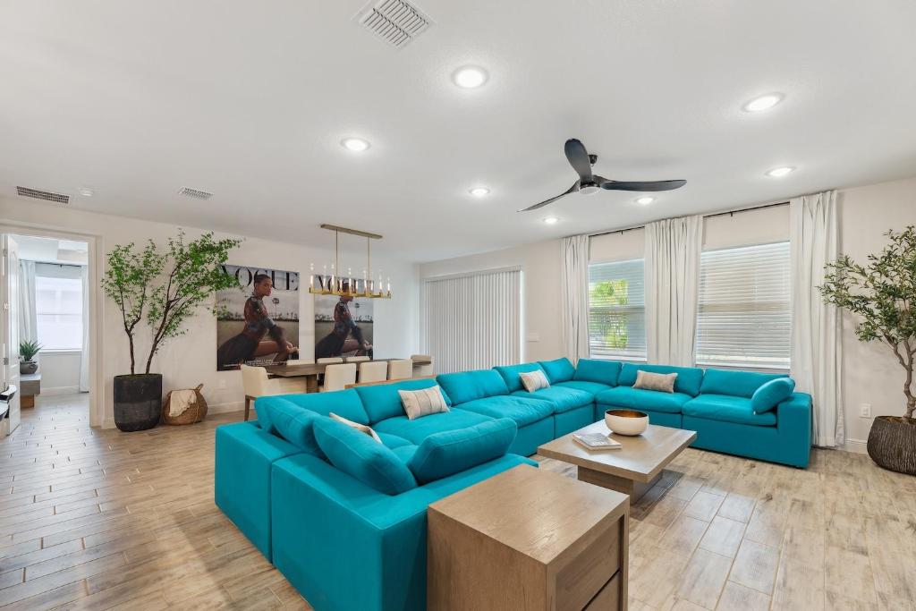 a living room with a blue couch and a table at Modern 5BR Getaway, PS5 & Board Games - Port St. Lucie, Florida in Carlton