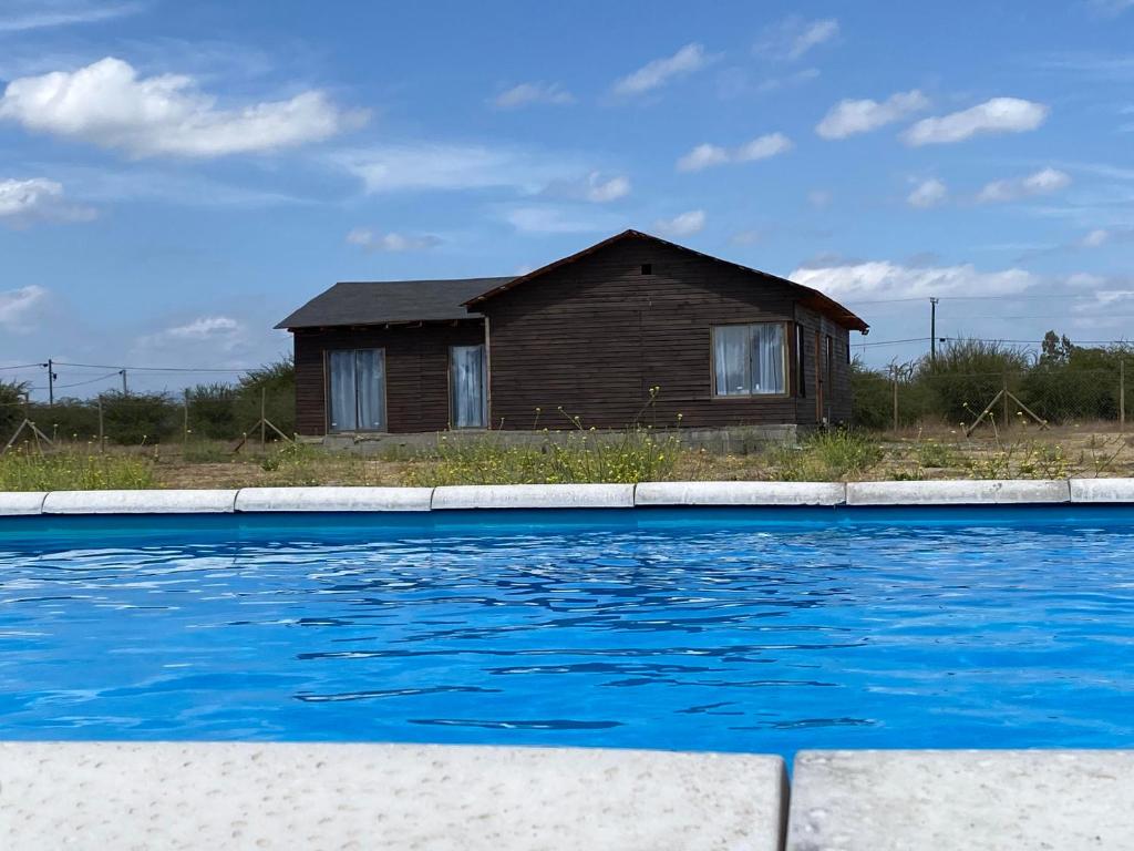PeralilloにあるCabaña con piscinaの家の前にスイミングプールがある家