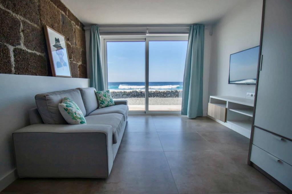 Una sala de estar con un sofá y vista al mar. en Apartamento Narcisa, en El Golfo
