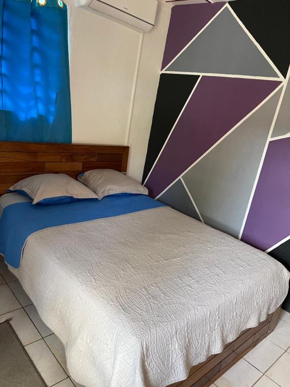 a bedroom with a bed with a geometric wall at Ouest Nelis Lodge in Saint-Laurent du Maroni