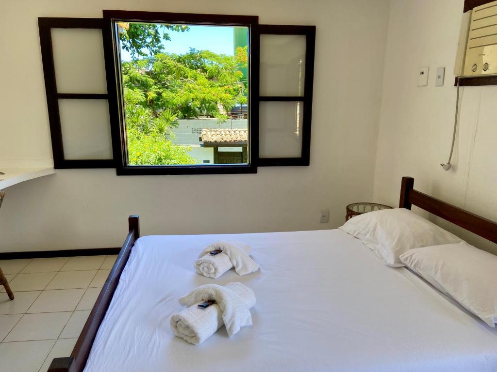 a bedroom with two towels on a bed with a window at Praia de Geribá C 4 in Búzios