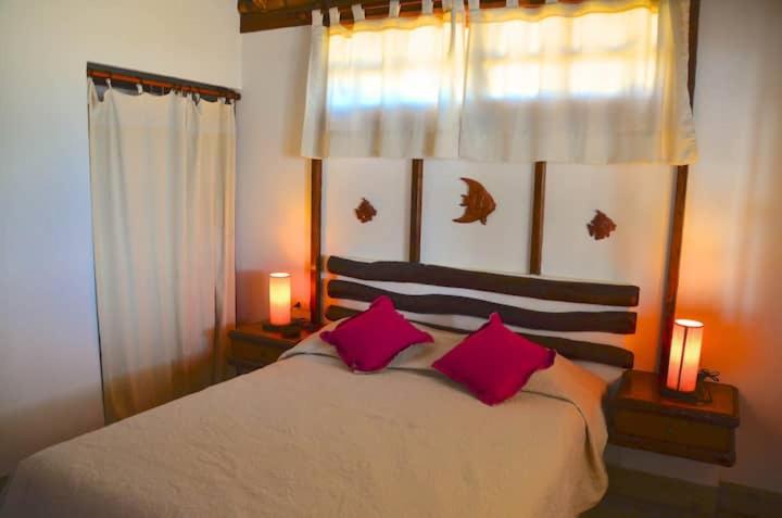 ein Schlafzimmer mit einem Bett mit zwei rosa Kissen in der Unterkunft Kalua Plateritos in Plateritos