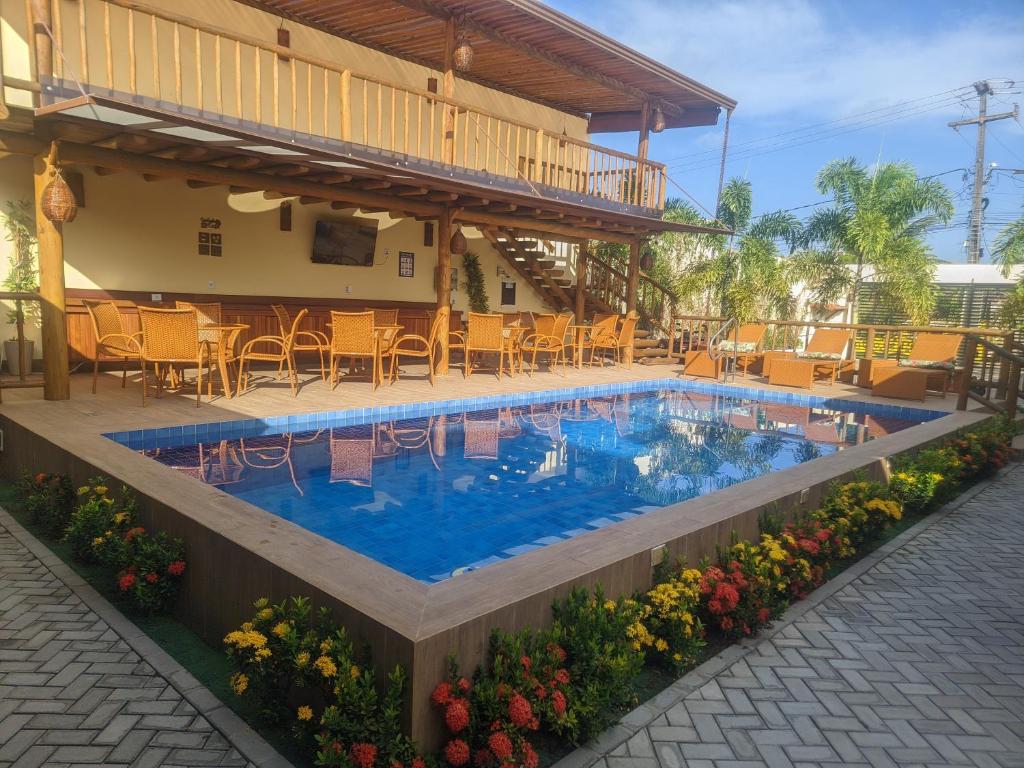 a pool with chairs and flowers in front of a building at Pousada Lua Nova Charmosa Pipa in Pipa