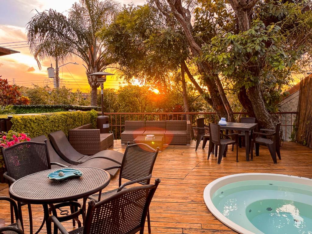 un patio con mesas y sillas y una bañera de hidromasaje. en Bambú Lodge San Jose Airport, en Ciudad Cariari