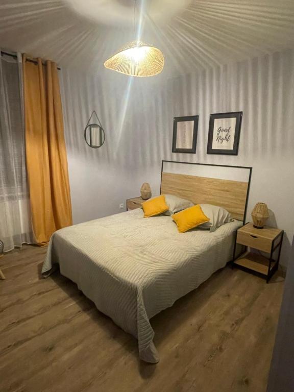 une chambre avec un grand lit avec des oreillers jaunes dans l'établissement Le petit sanvignard, à Sanvignes-les-Mines