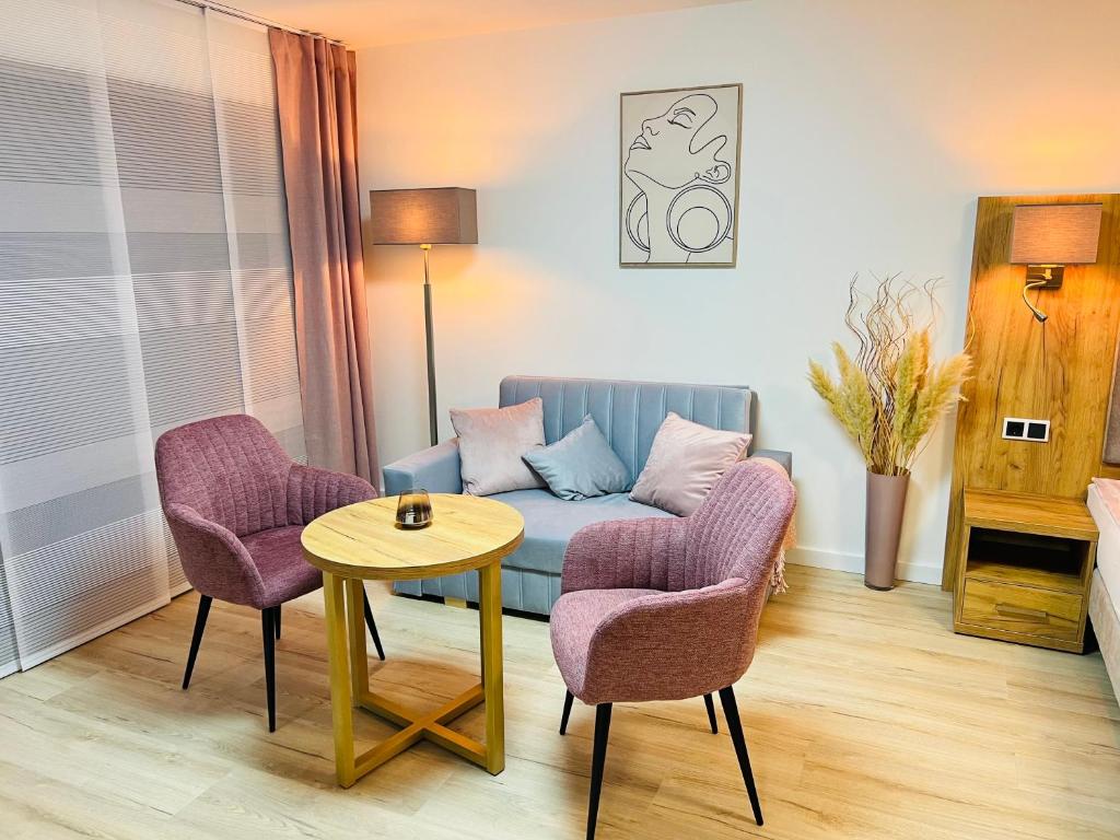 een woonkamer met een bank, 2 stoelen en een tafel bij Apartment „Amalia“ in Ergersheim