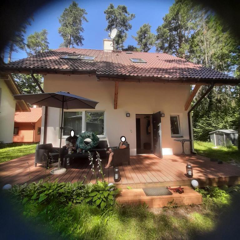 a house with a deck with two people sitting on it at Fiszka in Pobierowo