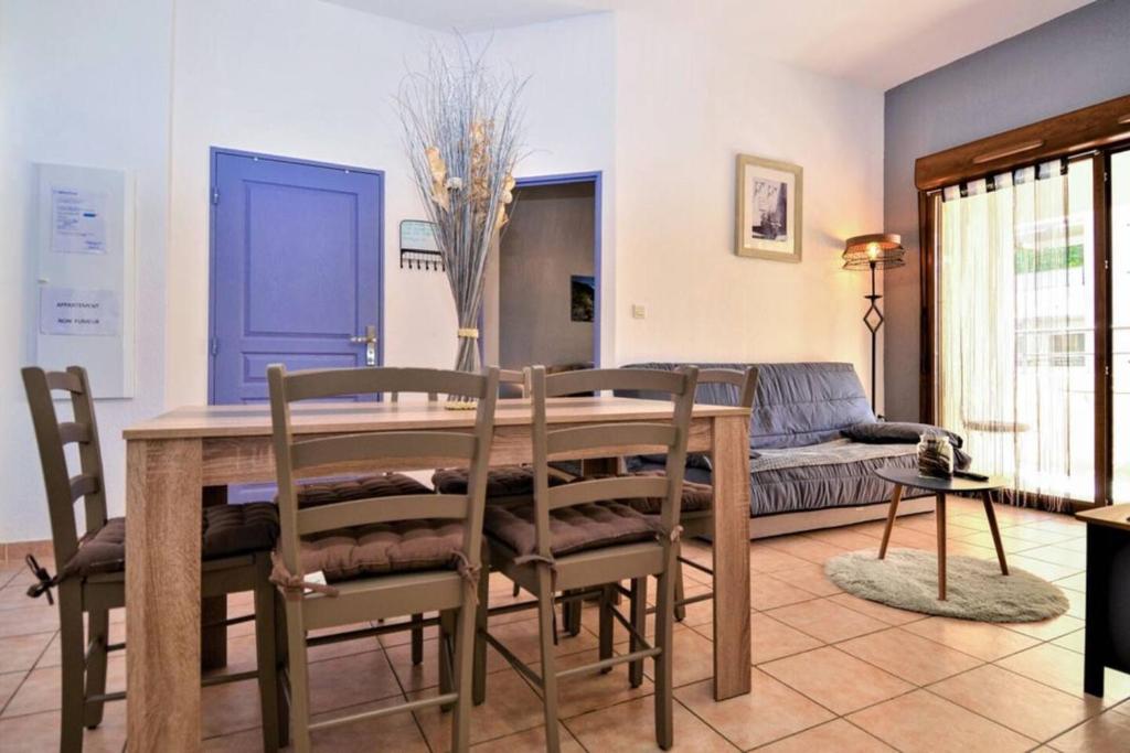 a dining room with a table and chairs and a couch at Propriete de 2 chambres avec piscine partagee terrasse et wifi a Uzes in Uzès