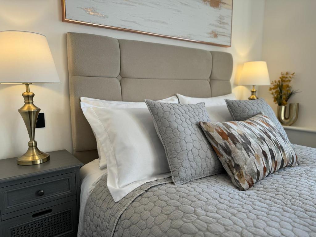 a bedroom with a large bed with pillows and a lamp at Elegant One Bedroom Apartment in Swindon