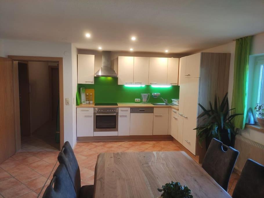 een keuken met een tafel en een groene muur bij Ferienwohnung in Weyregg am Attersee in Weyregg