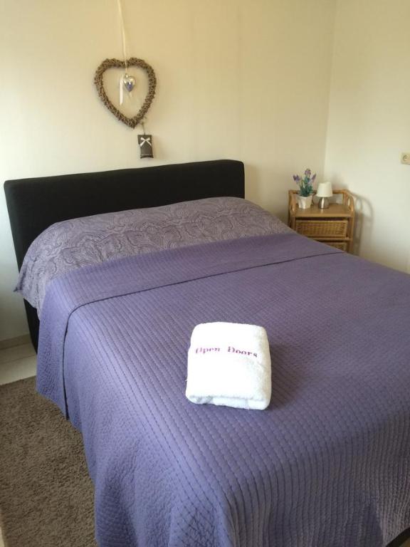 a bed with a purple blanket with a sign on it at Guest House Open Doors in Almere