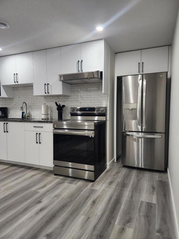 a kitchen with stainless steel appliances and white cabinets at Trendy 2-Bed Oasis Awaits! in Calgary