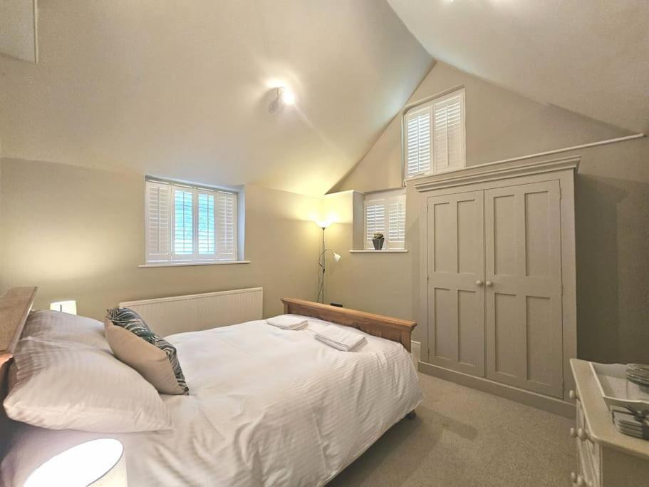 1 dormitorio con 1 cama blanca y 2 ventanas en The Old Stables - Self Contained Cottage - Hot Tub and Pool en Salisbury