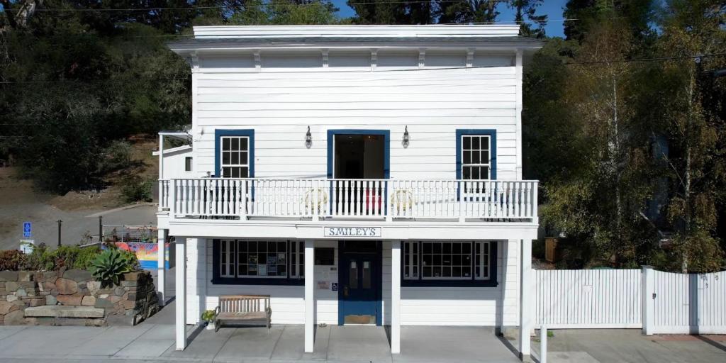 a white house with two dogs on a balcony at Smiley's Saloon & Hotel in Bolinas