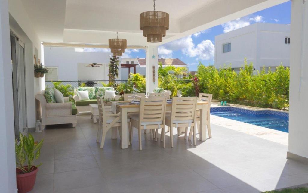a patio with a table and chairs and a pool at Dream villa with pool & garden view in Vista Cana in Punta Cana