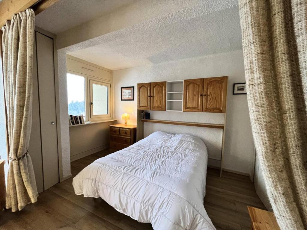 1 dormitorio con cama blanca y ventana en Résidence Les Glovettes - Studio pour 6 Personnes 234 en Villard-de-Lans