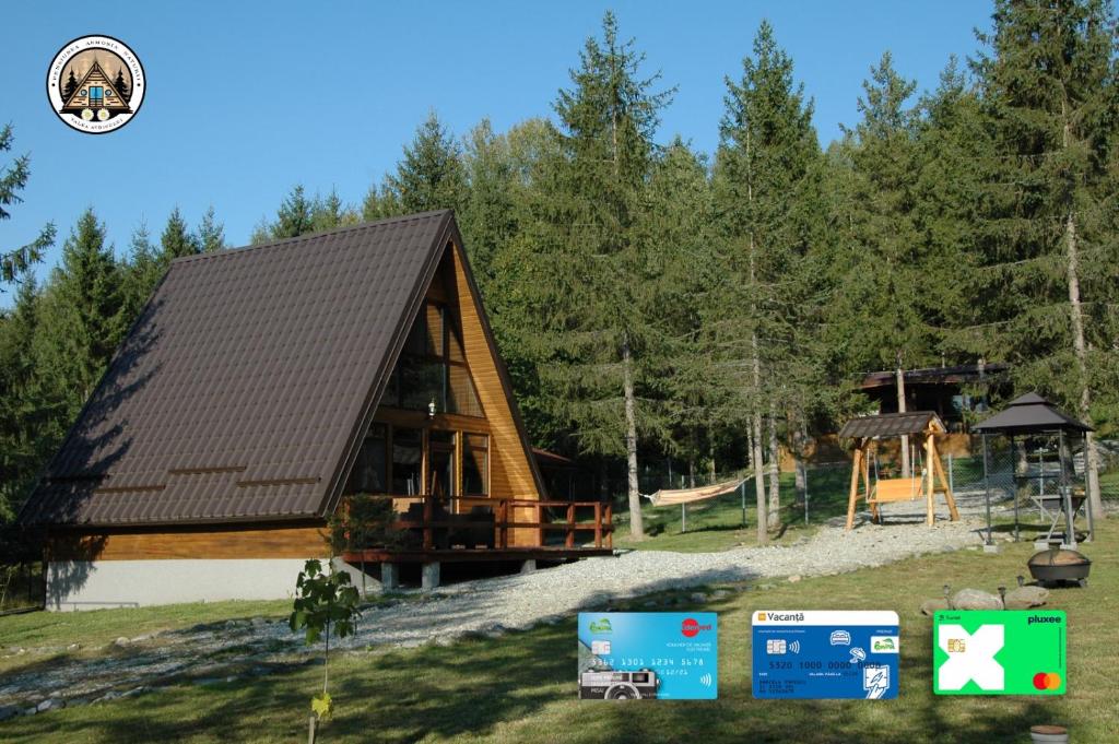 una baita di tronchi con parco giochi in una foresta di Cabana Armonia Naturii a Avrig