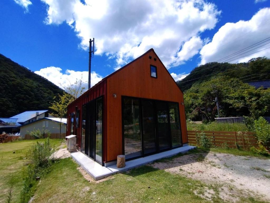 uma pequena casa vermelha com janelas de vidro num campo em Ayu no Sato Park Campsite - Vacation STAY 42240v em Shōbara