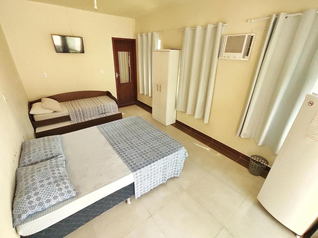 a small bedroom with two beds in it at Pousada Areia Nova in Garopaba