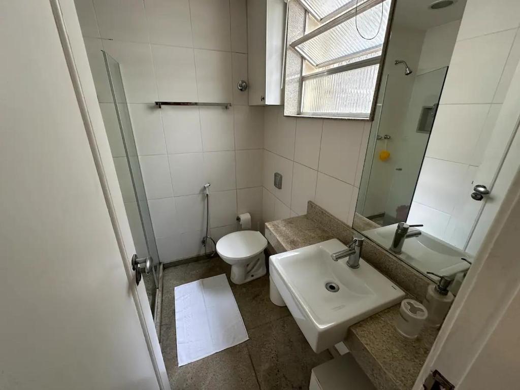 La salle de bains est pourvue d'un lavabo, de toilettes et d'un miroir. dans l'établissement Suíte no Jardim Botânico, à Rio de Janeiro