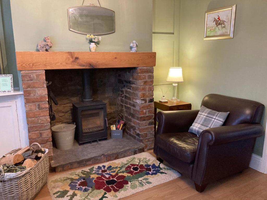 een woonkamer met een open haard en een leren stoel bij Adlington Cottage, Lancashire in Adlington