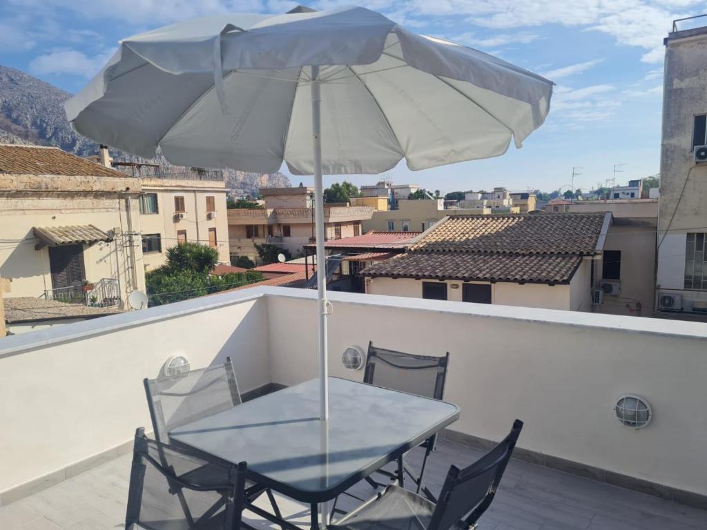 een tafel en stoelen op een balkon met een parasol bij Casetta Bella Nonna Rosetta in Mondello