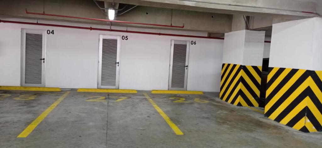 een rij witte deuren op een parkeerplaats bij Lujosa Suite; confort, seguridad in Guayaquil