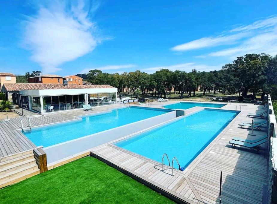 une grande piscine avec une terrasse en bois dans l'établissement Appartement proche de Saint Cyprien, à Lecci