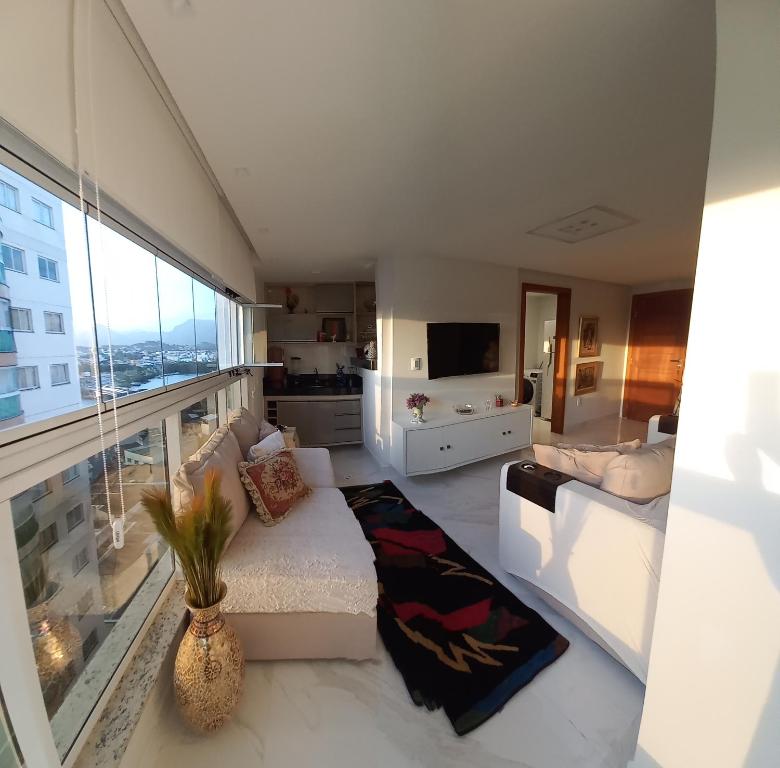 sala de estar con sofá y ventana grande en Apto confortável a 3 minutos praia. en Guarapari