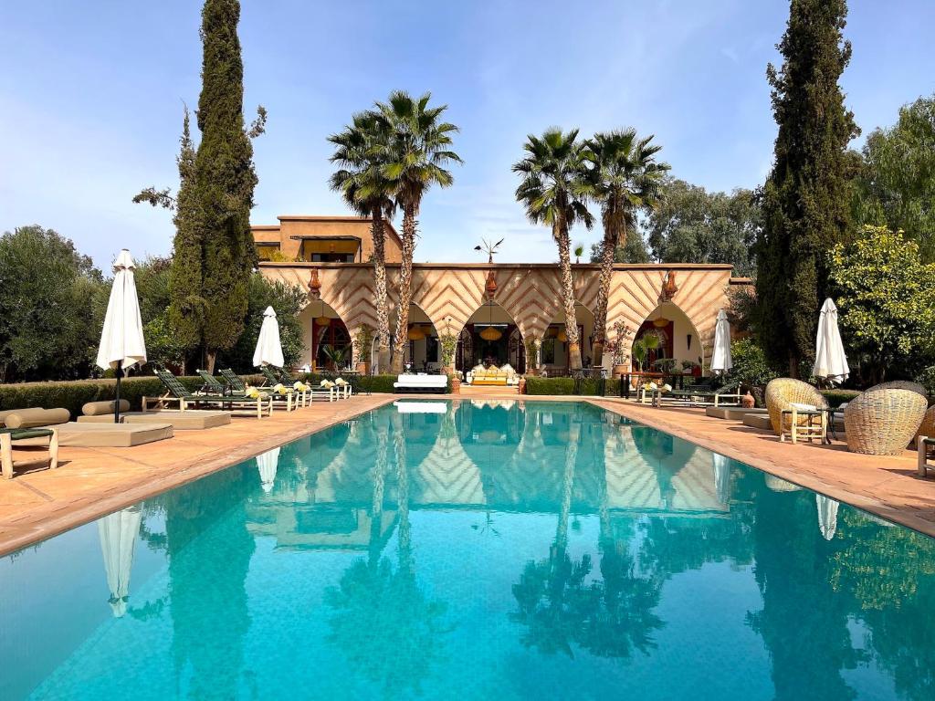 einem Pool mit Stühlen und Sonnenschirmen vor einem Gebäude in der Unterkunft Palais Dobra in Marrakesch