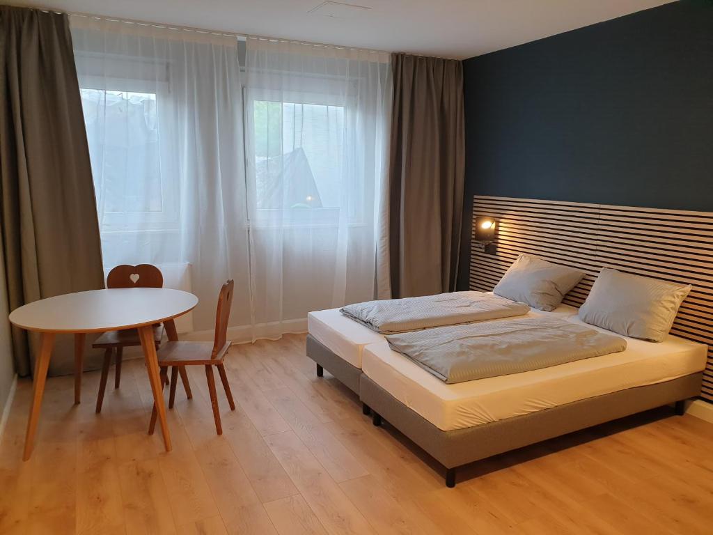 a bedroom with a bed and a table and a window at Novitel Apartements Heimstetten in Kirchheim