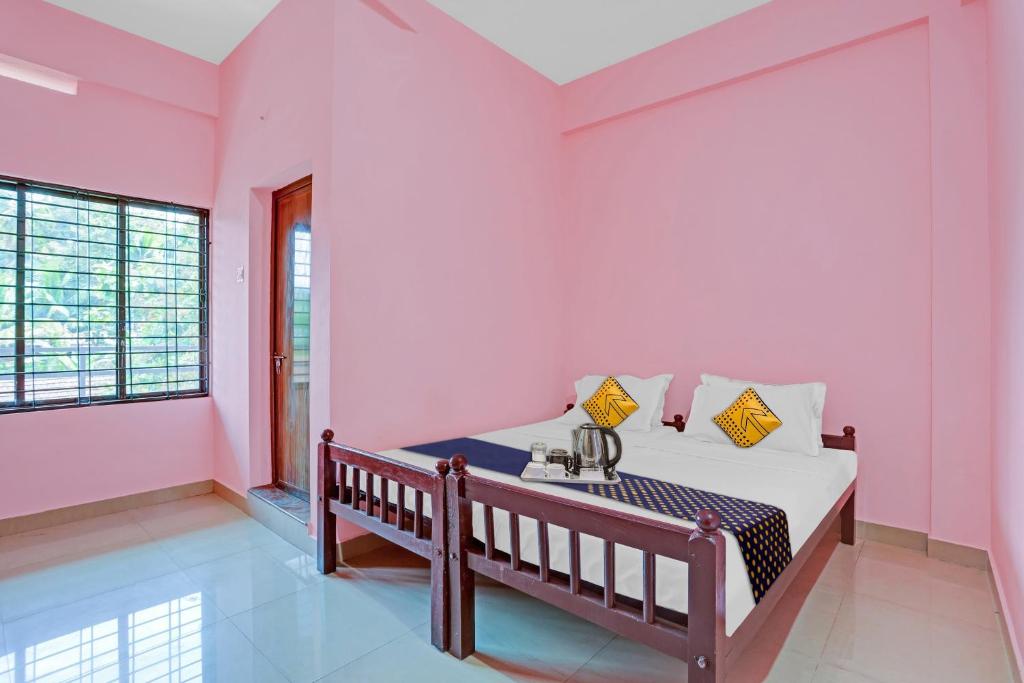 een slaapkamer met roze muren en een bed met een wastafel bij SPOT ON Greenland Residency in Pathanāmthitta