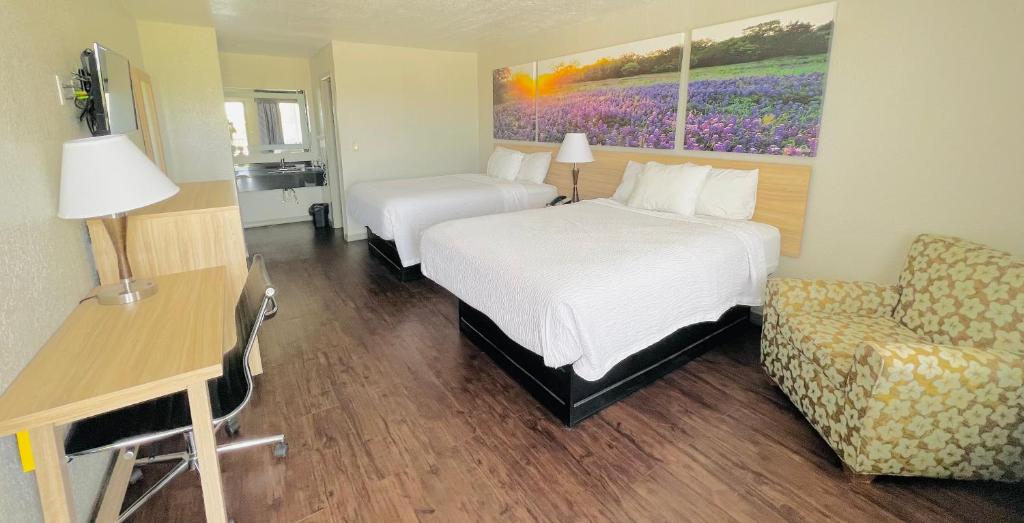 Habitación de hotel con 2 camas, escritorio y silla en Days Inn & Suites by Wyndham - Canton First Monday Trade Days, en Canton