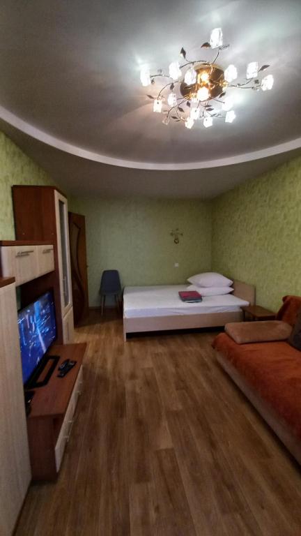 a bedroom with a white bed and a chandelier at Комфортная 1-комнатная Новопречистенская 1 in Cherkasy