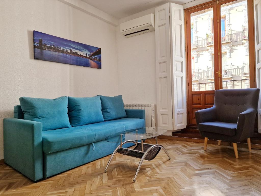 a living room with a blue couch and two chairs at Calle Mayor, alójate en el centro histórico de Madrid in Madrid