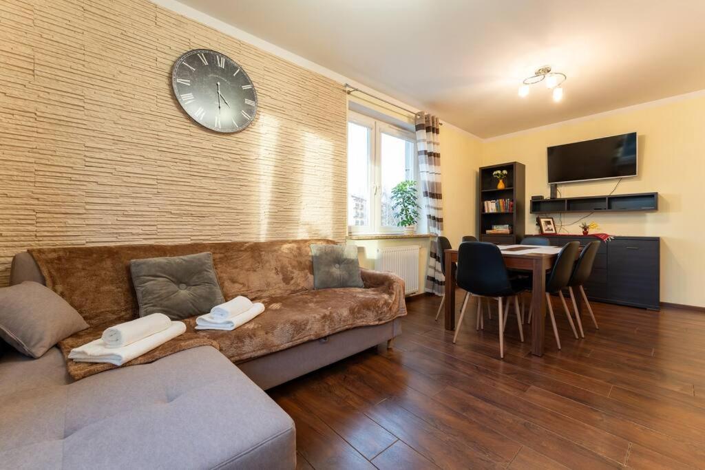 a living room with a couch and a clock on a wall at Apartament Rodzinny dla 6 osób - funkcjonalny - Space Apart in Jelenia Góra