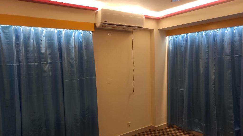 a room with blue curtains and a air conditioner at Signature Home in Dhaka