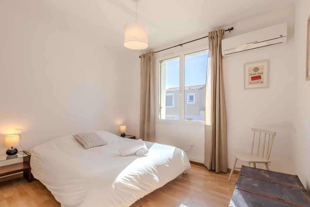 een slaapkamer met een wit bed en een raam bij L'oranger - Villa avec piscine in Saint-Jean-de-Védas
