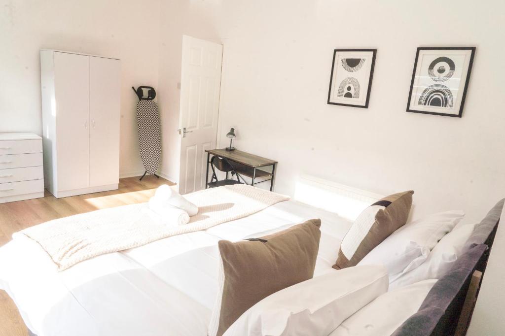a white bedroom with a large white bed with pillows at Mideyah Stays - 3 Bed Comfy House in Cardiff