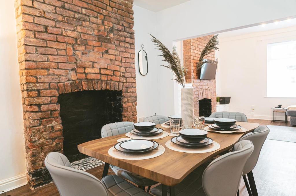 a dining room with a table and a brick fireplace at Mideyah Stays - 3 Bed Comfy House in Cardiff